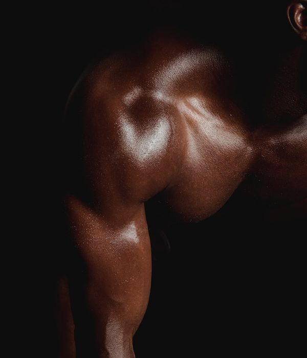 Man performing a difficult strength exercise in a dark gym with cyan highlights.